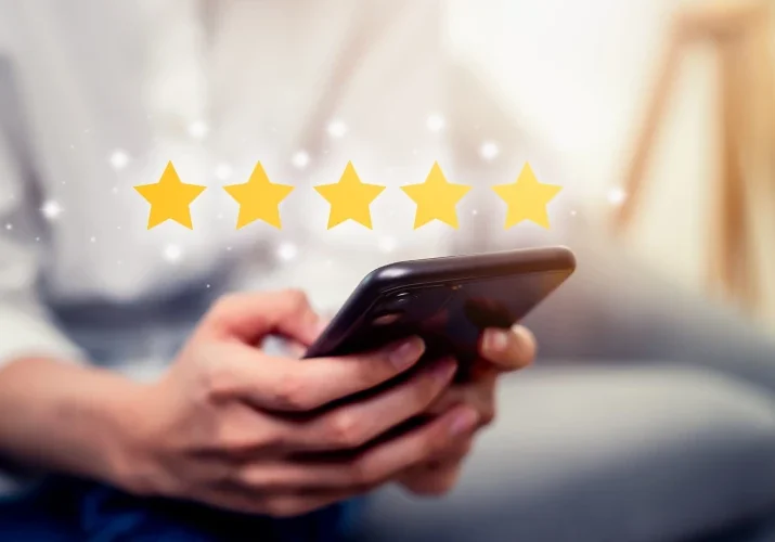 person holding a phone with a graphic of five stars above it